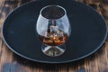 Glass of brandy with ice cubes/Glass of brandy with ice cubes on a black tray Royalty Free Stock Photo