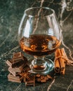 Glass of brandy on a old wooden table with a chocolate, cinnamon sticks Royalty Free Stock Photo