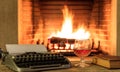 Glass of brandy and a typewriter on burning fireplace background Royalty Free Stock Photo