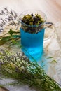 A glass brewer full of blue butterfly pea tea, with purple flowe