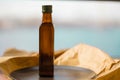 A glass brown transparent faceted bottle full Without labels with vegetable oil stands on a black plate on paper. Salad dressing.