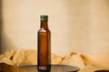 A glass brown transparent faceted bottle full with vegetable oil with green metal cap stands on a black plate on paper. Salad dres Royalty Free Stock Photo