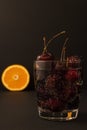 Glass with bubble beverage alcohol soda drink cocktail full of red fresh cherries with sticks and a slice of orange on backside is Royalty Free Stock Photo