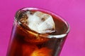 Glass of Bubbly Cola with ice cubes on a purple background Royalty Free Stock Photo