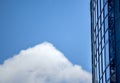 Glass building against the blue sky with small clouds. Business offices in a skyscraper with panoramic windows. Glass metal Royalty Free Stock Photo