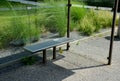 Glass bus stop with a metal bench for passengers in the city near the park. the glasses are connected by metal clips. a flower bed Royalty Free Stock Photo