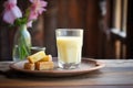 glass of buttermilk on rustic wood with fresh butter cubes