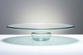 A glass cake plate on a white table, glass podium, pedestal.