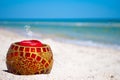 Glass candlestick and a red candle on the sand on a background of blue sea and blue sky Royalty Free Stock Photo