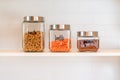 Glass canisters lined up on a kitchen shelf