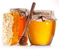Glass cans full of honey, honeycombs and wooden stick.
