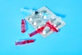 Glass capsules with red vaccine near pills and syringe on blue background Royalty Free Stock Photo