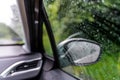 The glass of the car window and rear-view mirrors in raindrops. Abstract travel transport background