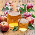 Glass and carafe of fresh apple juice and organic apples on dark old wooden table Royalty Free Stock Photo