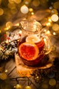 Glass carafe with fruit tea and a piece of lemon in it on a wooden table with bokeh and christmas lights Royalty Free Stock Photo