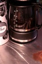A glass carafe almost half full stands in a coffee machine. Coffee stains is seen on the countertop Royalty Free Stock Photo