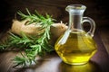 a glass carafe of olive oil next to rosemary sprigs