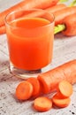 Glass of carrot juice and fresh carrots on white wooden background. Royalty Free Stock Photo
