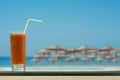 A glass of carrot juice with a straw in the cafe on the tropical beach backgrounds