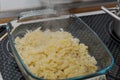 Glass casserole dish with cheese Spaetzle, a south german specialty food made of lumps of dough standing on oven