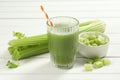 Glass of celery juice and fresh vegetables on white wooden table Royalty Free Stock Photo