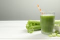 Glass of celery juice and fresh vegetables on white wooden table, space for text Royalty Free Stock Photo