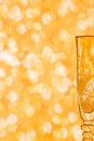 Glass of champagne against blurred golden background.