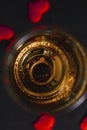 A glass of champagne with an engagement ring on a black background with confetti made of red hearts. selective focus. Top view Royalty Free Stock Photo