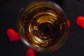 A glass of champagne with an engagement ring on a black background with confetti made of red hearts. selective focus. Top view Royalty Free Stock Photo