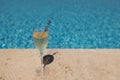 Glass of champagne with sprig of lavender against poolside at resort hotel during vacation