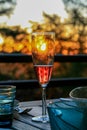 Glass of champagne or wine on table on terrace during evening. Sunset and trees in the background. Home comfort, relaxation, calm Royalty Free Stock Photo