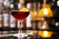 Glass of cherry color alcohol cocktail decorated with orange slice at bar counter backgound. Royalty Free Stock Photo