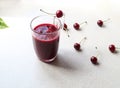 A glass of cherry juice in a glass mug on the kitchen table with scattered cherries, side view Royalty Free Stock Photo