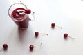 A glass of cherry juice in a glass mug on the kitchen table with scattered cherries, top view-the concept of drinking freshly Royalty Free Stock Photo