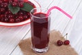 Glass of cherry juice and plenty of ripe cherries