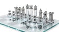 A glass chess board with silver metal chess pieces arranged in starting positions on a white background for strategy games Royalty Free Stock Photo