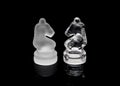 Chess glass figures of horses on a dark background. Confrontation concept