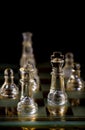 Glass chess pieces are defending the king on board in dark Royalty Free Stock Photo
