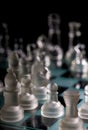 glass chess pieces are defending the king on board in dark