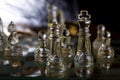 Glass chess pieces are defending the king on board in dark Royalty Free Stock Photo