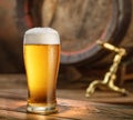 Glass of chilled beer and wooden beer cask on the background