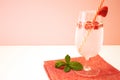 A glass of chilled carbonated lemonade with raspberries stands on a red napkin on a white table against a pink wall. Royalty Free Stock Photo