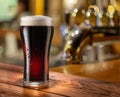 Glass of chilled stout beer on wooden bar table top and blurred bar interior at the background Royalty Free Stock Photo