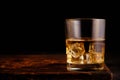 Glass chilled whiskey with ice cubes on wooden background
