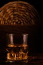 Glass chilled whiskey with ice cubes on wooden background in cellar