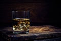 Glass chilled whiskey with ice cubes on wooden background in cellar