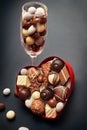 Glass with chocolate pralines and heart shaped box with pralines Royalty Free Stock Photo