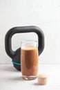 Glass of Chocolate Protein Shake with milk and banana, Whey protein in scoop and black sporting kettlebell in background. Sport nu Royalty Free Stock Photo