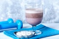 Glass of Chocolate Protein Shake with milk and black currant. L - Carnitine and blue dumbbells in background. Sport nutrition Royalty Free Stock Photo