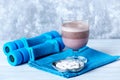 Glass of Chocolate Protein Shake with milk and black currant. L - Carnitine and blue dumbbells in background. Sport nutrition Royalty Free Stock Photo